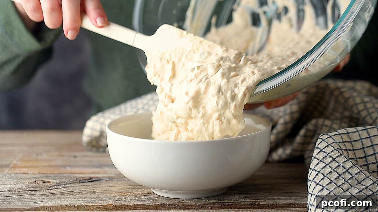Transferring jalapeno popper dip to an oven-safe serving dish.