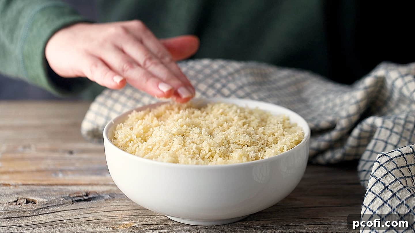 Layering buttered cheesy breadcrumbs over the dip.