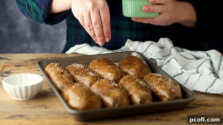 Oiling and generously sprinkling kosher salt onto the prepared potato skins before the second bake.