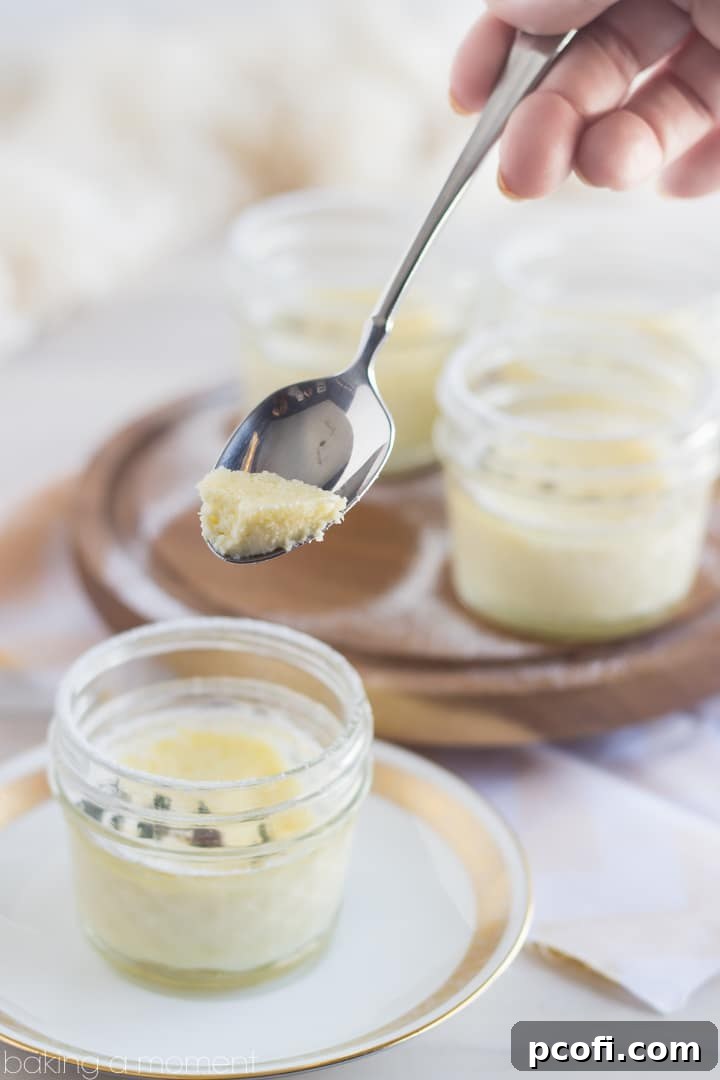 Vertical shot of two Meyer Lemon and Thyme Pots de Creme, garnished with fresh thyme and powdered sugar, ready to be served.