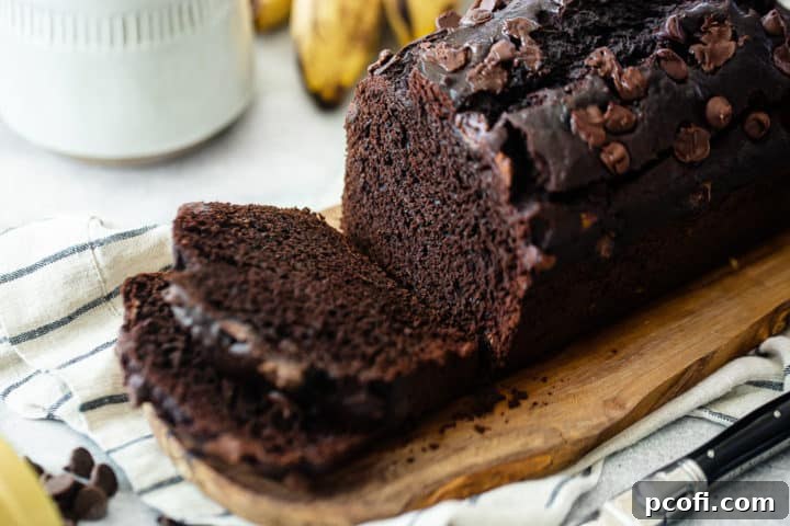 Close-up of a sliced chocolate banana bread loaf, revealing its moist, cakey interior with visible banana and chocolate pieces.