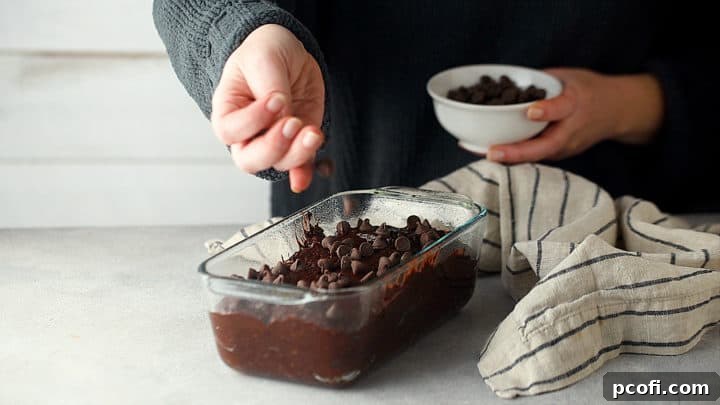 Sprinkling unbaked chocolate banana bread loaf with chocolate chips for garnish before baking.