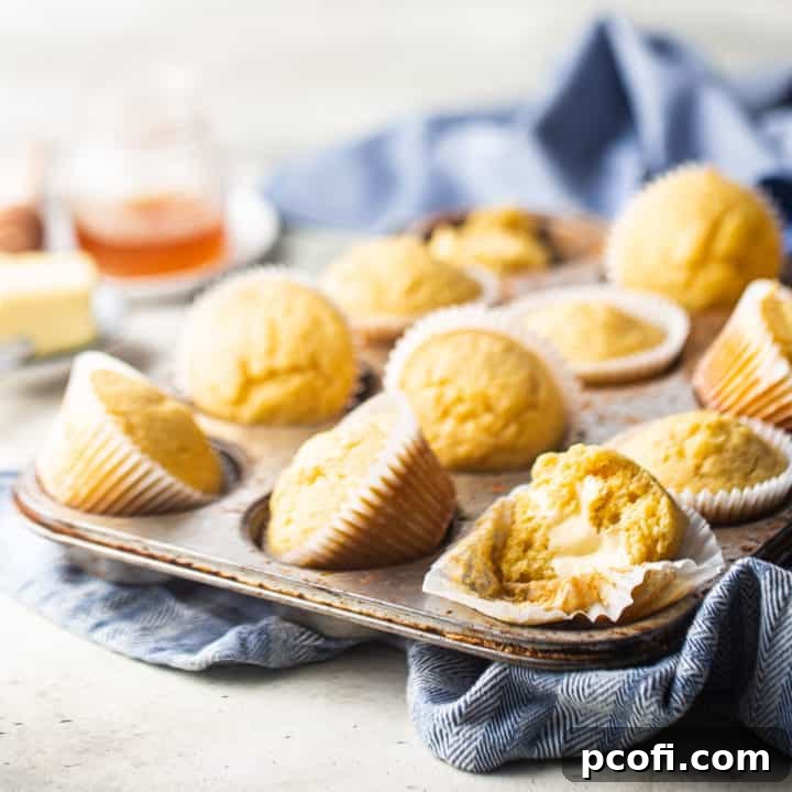 Freshly baked cornbread muffins in a vintage muffin tin with a blue kitchen towel, ready to be served.