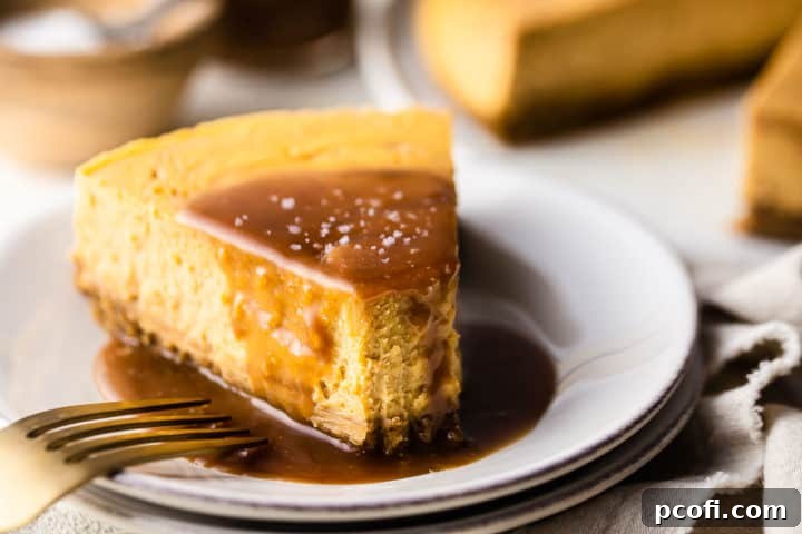 Salted caramel cheesecake recipe, baked, sliced and served on a white plate with a gold fork.