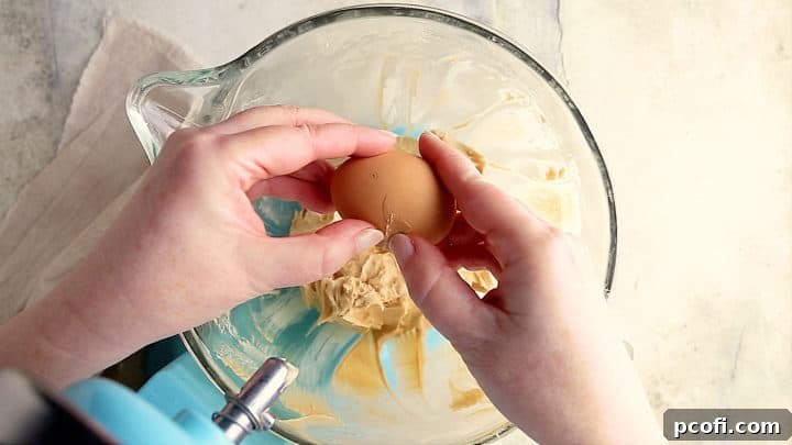 Adding eggs to caramel cheesecake batter.