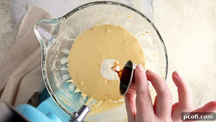 Adding cream and vanilla to caramel cheesecake filling.