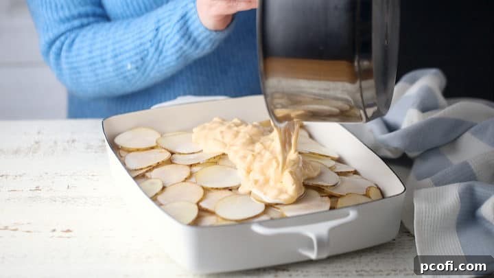 Pouring sauce over cheesy scalloped potatoes.
