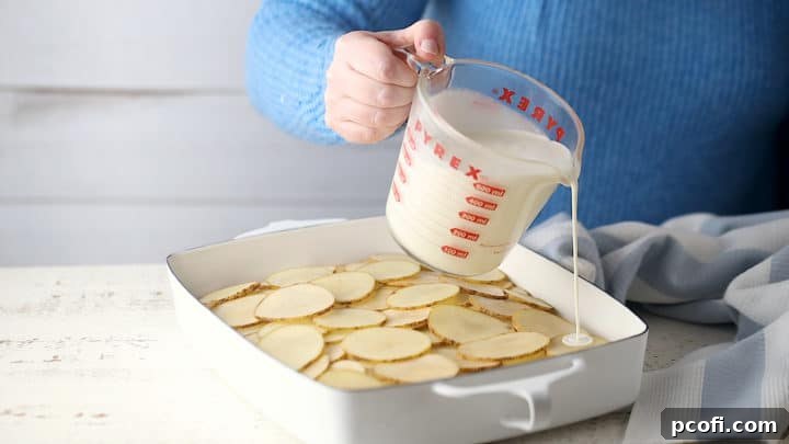 Submerging the sliced potatoes in the cream/milk mixture.
