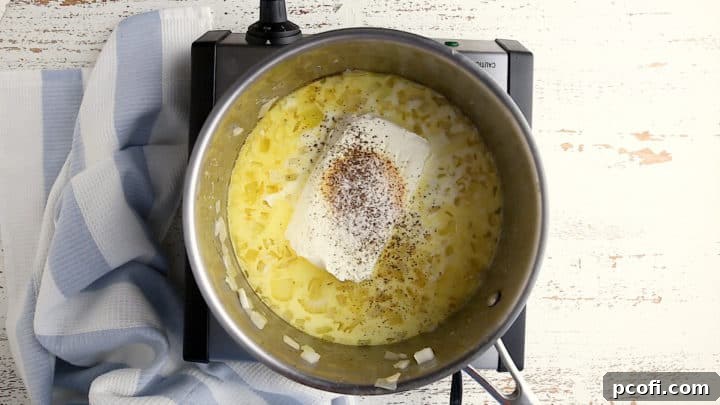 Adding cream cheese and seasonings to sauteed onion, cream, and milk mixture.