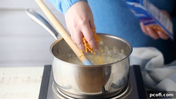 Stirring shredded cheese into scalloped potatoes sauce.