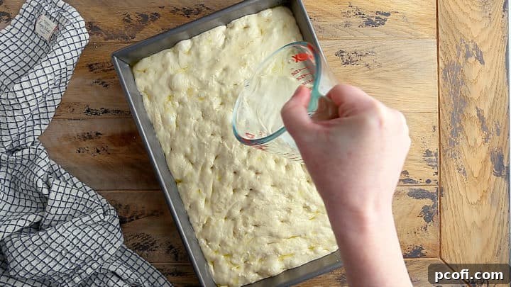 Pouring brine over unbaked focaccia.