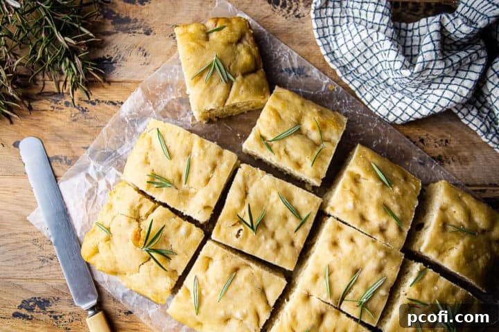 Overhead image of focaccia bread recipe, prepared and garnished with sea salt and fresh herbs.