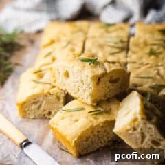 Focaccia cut into squares and stacked on a wooden board.