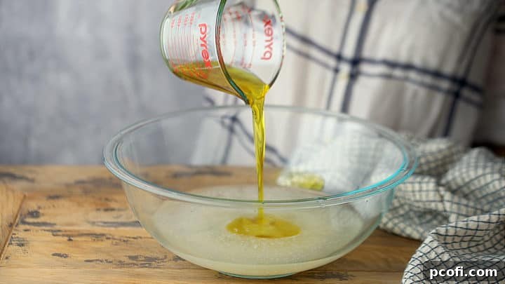 Adding olive oil to the yeast mixture.