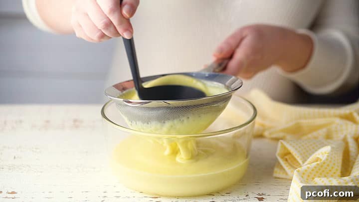 Homemade pudding is being passed through a fine-mesh sieve, ensuring a smooth, lump-free texture for the final dessert.