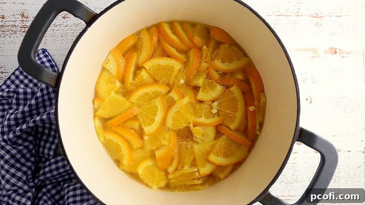 Simmering oranges in water in a large pot to soften their peels, a crucial step for tender marmalade.
