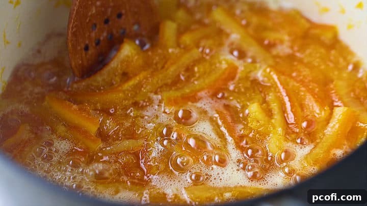 Boiling orange marmalade in a large pot until it reaches its gel point, creating a rich and thick preserve.