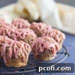 A close-up of a finished blood orange mini muffin, showing its moist crumb and citrus glaze