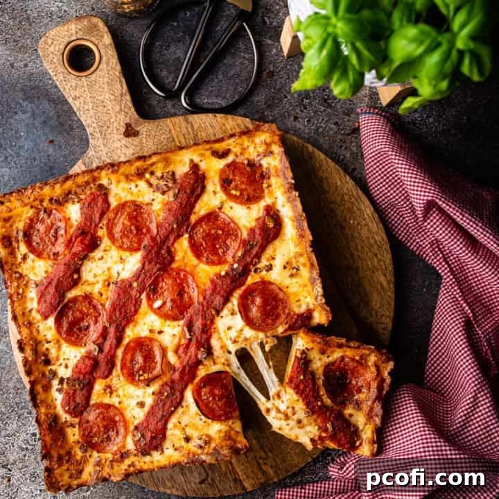 Overhead image of Detroit-style pizza on a wooden board with fresh basil, ready to be served.