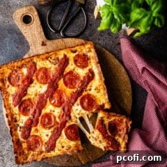 Overhead image of Detroit-style pizza on a wooden board with fresh basil.