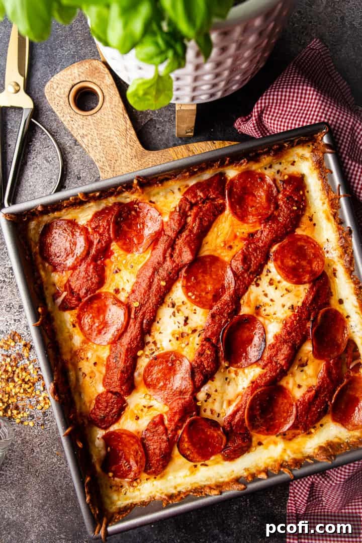 Overhead image of Detroit pizza in a square pan, with a red checked cloth for a rustic feel.