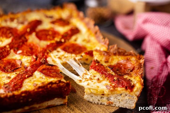 Close-up image of a slice of Detroit-style pizza being pulled, highlighting the thick, pillowy crust and stretchy melted cheese, perfect for a pizza party.