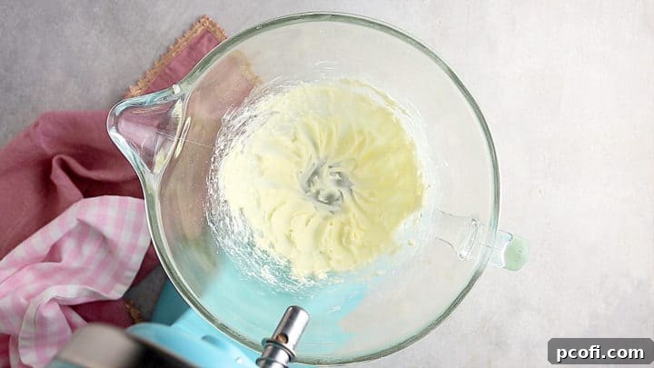 Cream cheese and powdered sugar being whipped together until smooth, forming the base of the filling.