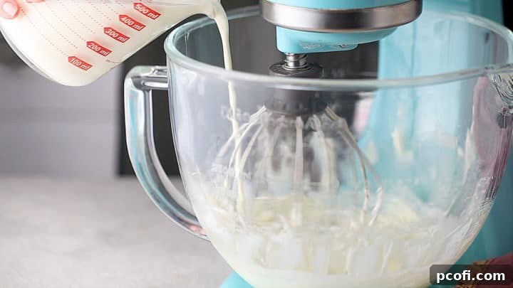 Slowly adding cold heavy cream to the cream cheese and powdered sugar mixture while mixing, for the cream puff filling.