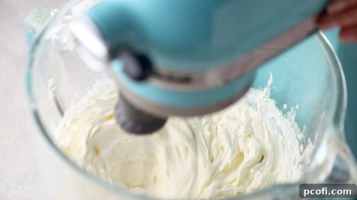 Stiffly whipped cream puff filling in a stand mixer bowl, indicating readiness.