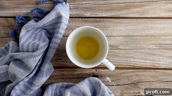 Melted butter in a white ceramic coffee mug, ready for dry ingredients.