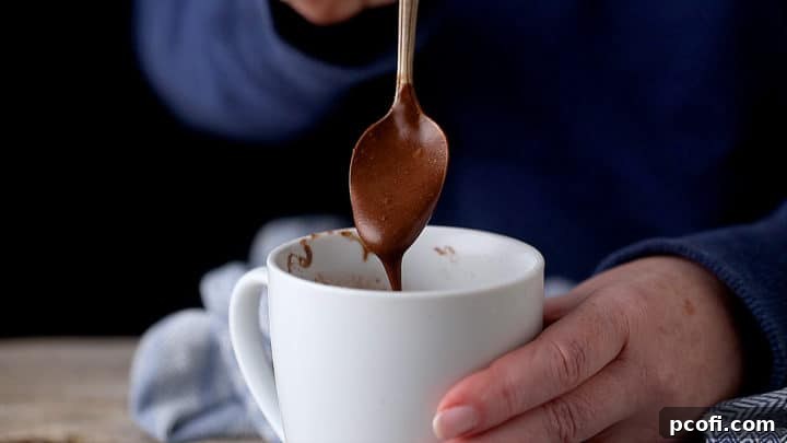 Smooth chocolate mug cake batter in a white ceramic coffee mug, ready for chocolate chips.