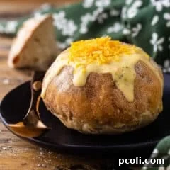 Bread bowl filled with soup on a dark plate with a copper spoon.