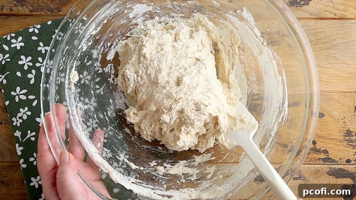 Sticky bread dough in a glass mixing bowl.