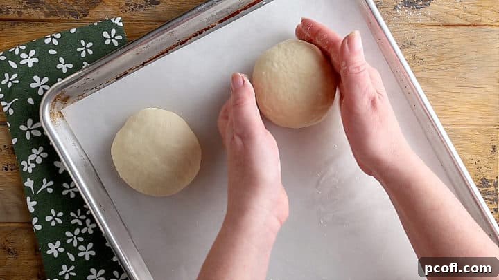 Placing unbaked bread dough on a baking sheet to rise.