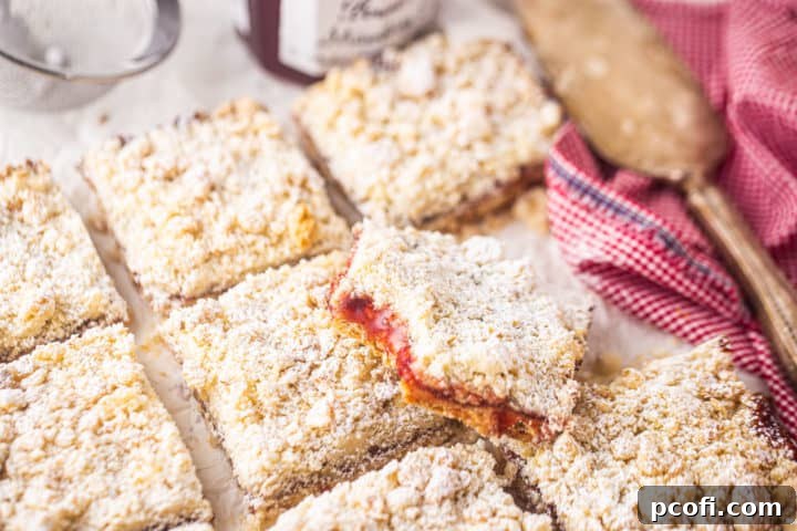A delectable strawberry jam bar, prepared and elegantly served on a sheet of parchment paper with a silver cake server.