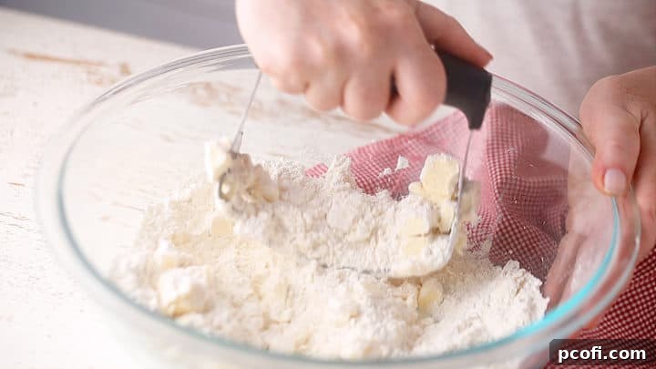 Cutting cold butter into dry ingredients for shortbread crust, ensuring a delicate texture.