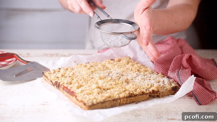 Dusting freshly baked strawberry jam bars with a delicate layer of powdered sugar.