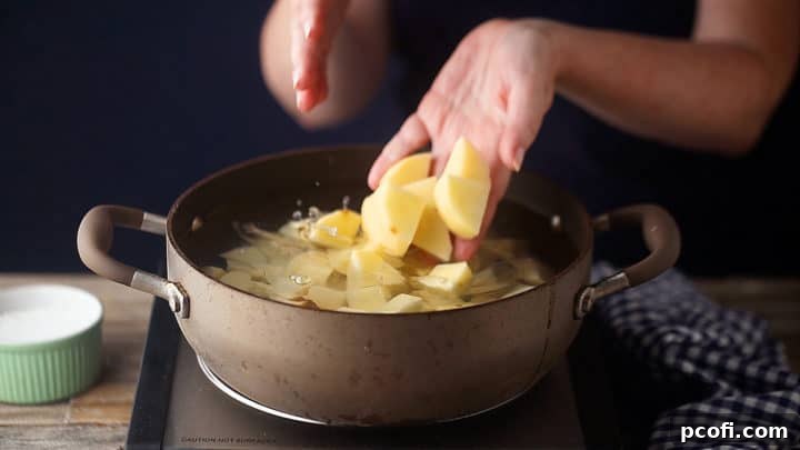 Dropping cubed potatoes into a pot of cold, salted water to cook for potato salad.