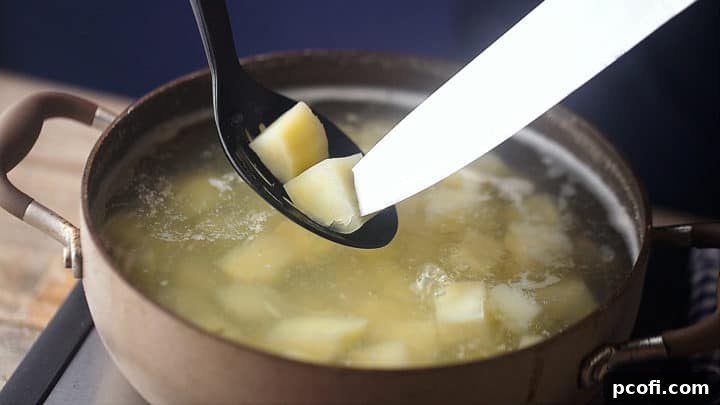 Checking potatoes for doneness with the point of a sharp knife for potato salad.