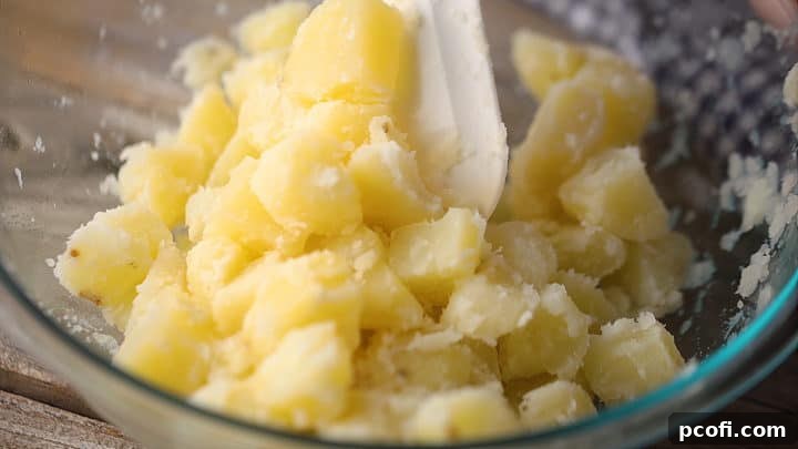 Tossing hot cooked potatoes in white vinegar for enhanced flavor in potato salad.