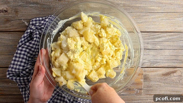 Folding cooked potatoes into the creamy dressing for potato salad.