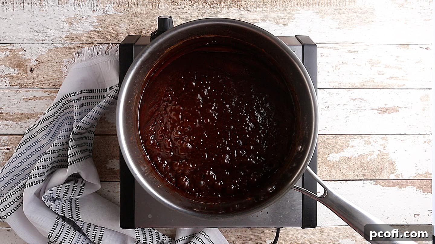 The chocolate and sugar mixture reaching a full rolling boil in a saucepan.