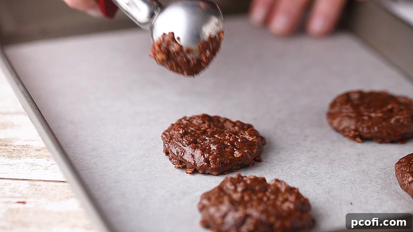 Freshly formed no-bake cookies cooling and setting on a parchment-lined baking sheet.