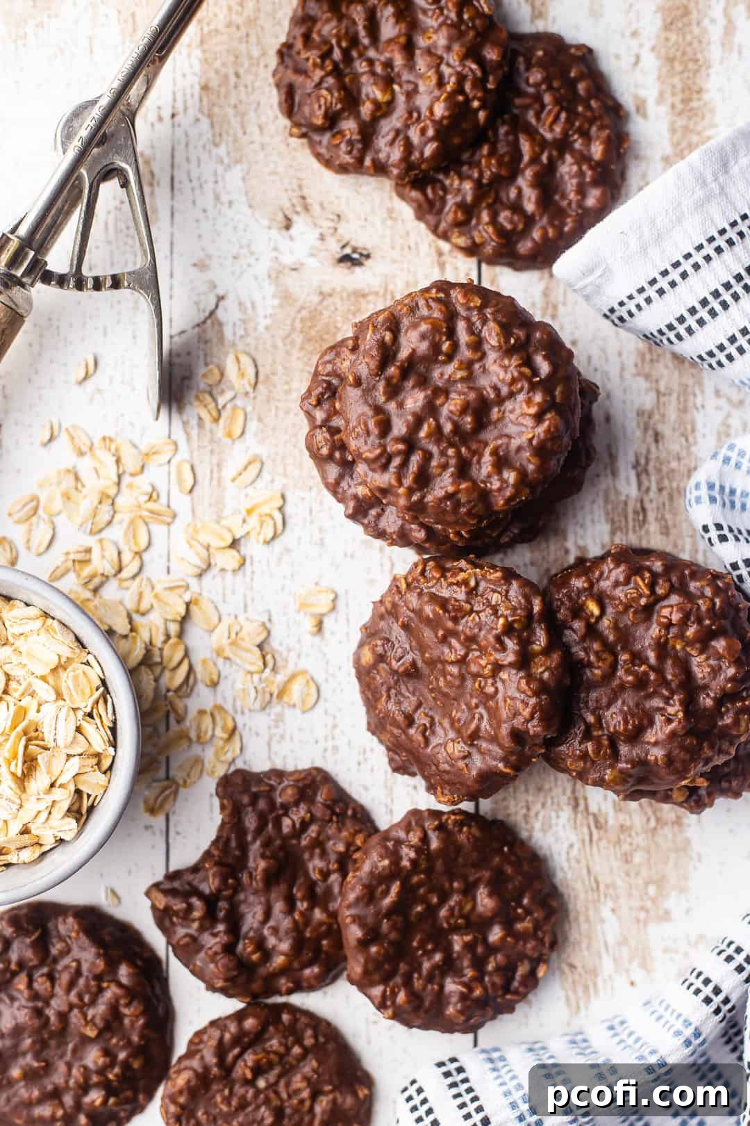 An overhead view of finished peanut butter no-bake cookies scattered on a rustic white table, ready to eat.