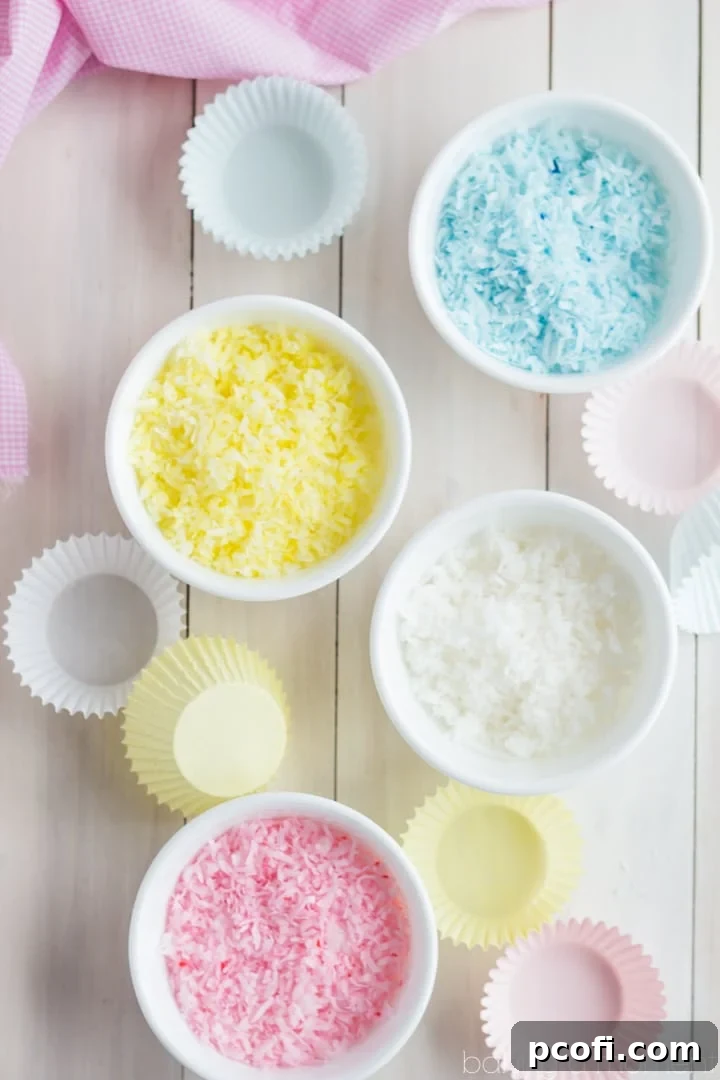A vibrant display of decorated cupcakes. Each one a tiny masterpiece, showcasing the rich chocolate cake beneath a generous swirl of marshmallow frosting, crowned with colorful pastel coconut flakes.