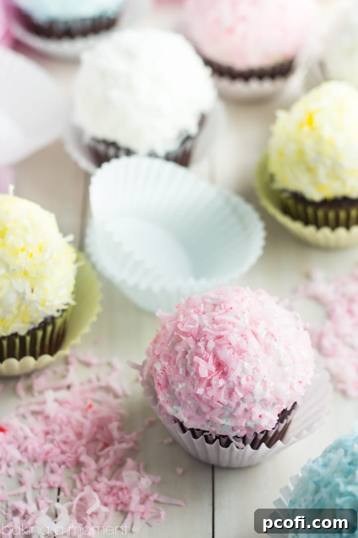Close-up of a beautifully coated pastel snowball cupcake. The light pink coconut flakes cling perfectly to the marshmallow frosting, making it an irresistible visual and culinary delight.