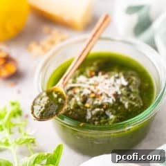 Pesto recipe, prepared and served in a shallow glass jar.