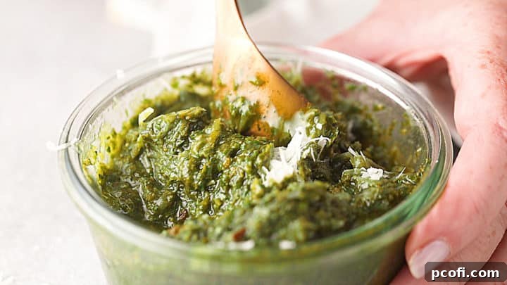 Folding freshly grated parmesan cheese into homemade pesto recipe.