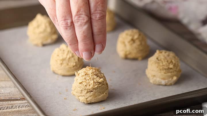 Sprinkling raw sugar on unbaked brown sugar cookies.