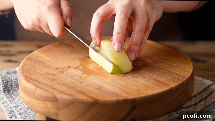 Cutting out the core of a peeled and quartered apple, a crucial step for the perfect pie filling.